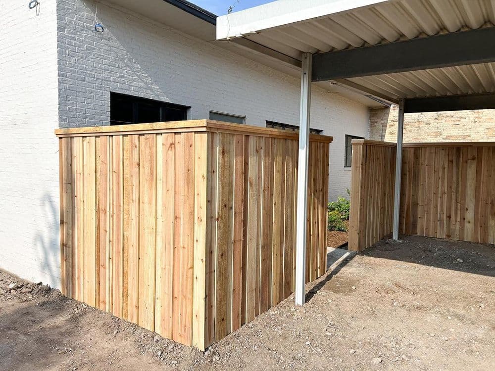 Wooden fence edges with fresh cedar planks, surrounding a residential outdoor space.