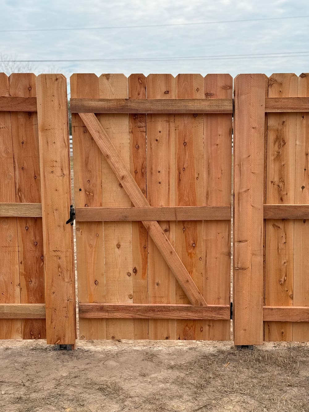 Wooden garden gate with a rustic design, set against a clear sky background.